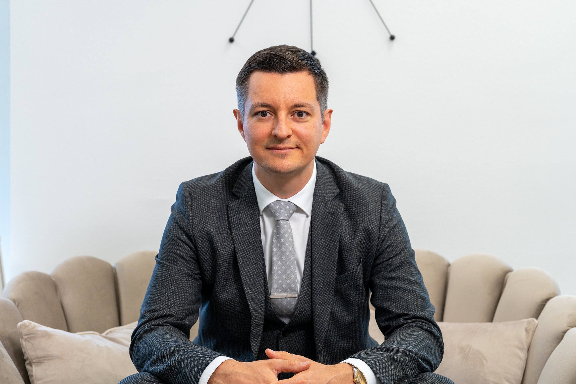 David Deindl, Gesch&auml;ftsf&uuml;hrer und Immobilienberater bei David Deindl Immobilien, l&auml;chelnd auf Couch